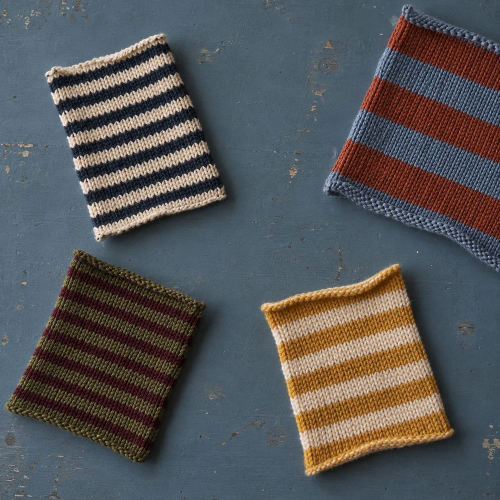 Four striped knitted textile swatches arranged on a blue surface.