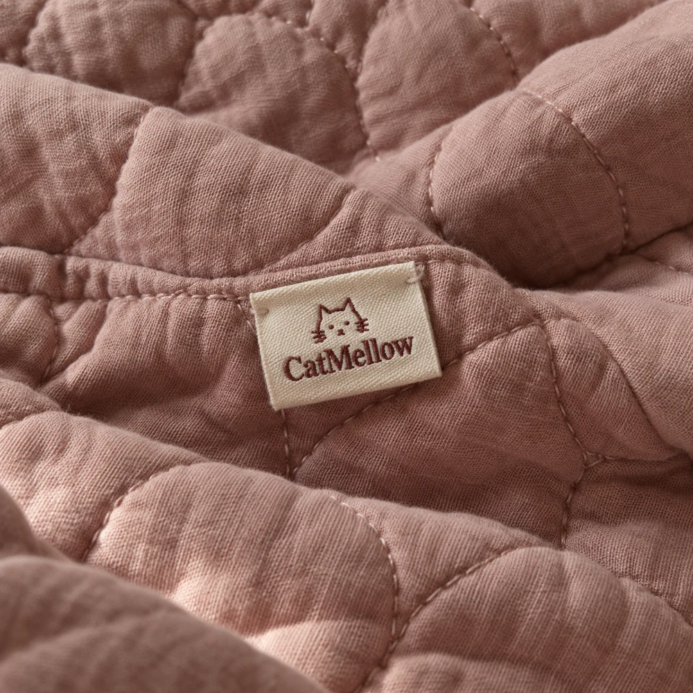 CatMellow woven label stitched onto soft rose-colored quilted fabric.